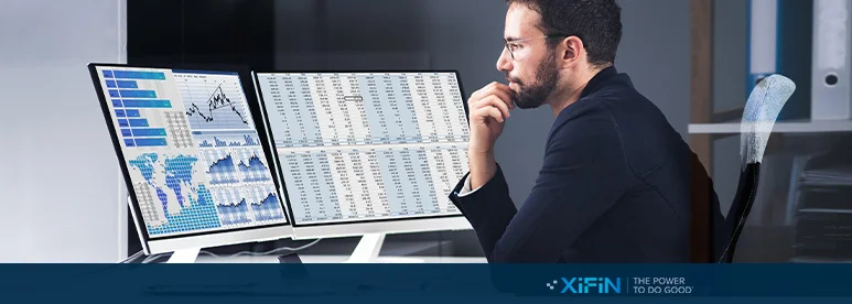 Gentleman sat at a desk studying charts and graphs on 2 screens directly in front of him